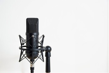 A sleek black microphone is positioned on a stand against white
