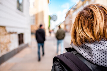 Rear View of People Walking on Urban Street Captured with Creative Focus Effect, Highlighting Youthful Style and City Life Atmosphere on a Bright, Sunny Day