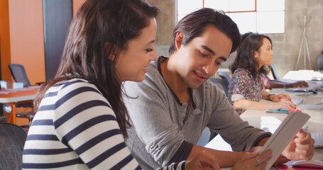 Male And Female Designers With Digital Tablet Meeting At Desks In Modern Office 