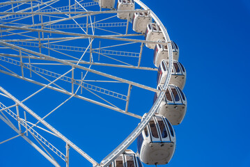 A detailed view of a Ferris wheel in San Francisco, showcasing its metal framework and enclosed...