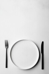 Minimalist background with just one plate, knife, and fork