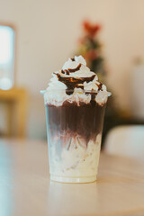 Delicious chocolate dessert in cup topped with whipped cream and syrup
