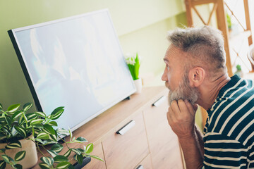 Fototapeta premium Elderly man with a beard enjoying a weekend moment indoors in a cozy living room