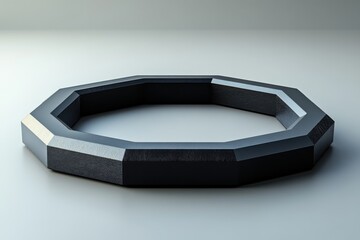 A geometric octagonal ring with a sleek black finish on a minimalist surface.