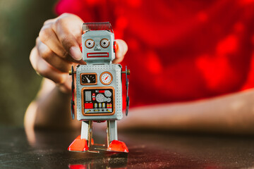 Naklejka premium vintage toy robot held by child, showcasing retro design and colorful features. robot has dials and buttons, evoking nostalgia and playfulness