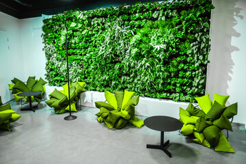 Modern Office Space With Indoor Vertical Green Wall and Stylish Seating Arrangement for Eco-Friendly Workplace Design and Relaxation Area