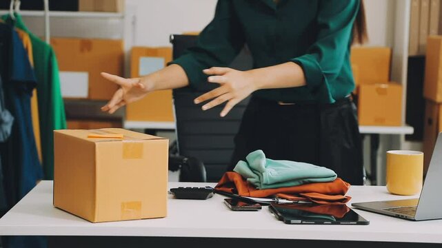 Successful young asian sme business owner working in a storage room and celebrating a successful order just received