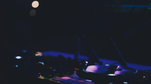 DJ work in a nightclub, mixing. A club DJ mixes music using an audio mixer and turntables on stage. A disc jockey plays in a club at a party.