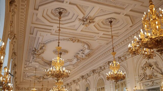 A stunning ballroom with an intricately designed ceiling adorned with golden chandeliers, ornate moldings, and decorative sculptures. The luxurious space exudes elegance and opulence, perfect for gran