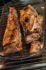 Juicy roasted meat in a glass dish cooking in the oven