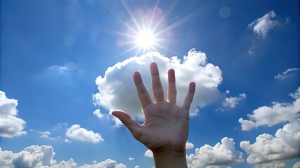 Hand Reaching Towards Bright Sun and Puffy Clouds in a Blue Sky