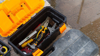 Top view of Black toolbox with yellow lid. Inside are stacked pliers, hammers, screwdrivers and other construction equipment. In construction site. Mechanic preparation concept. and space for text