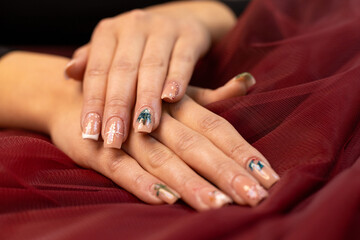 Christmas nail design, woman's hands with Christmas tree and candy cane design. Merry Christmas. Candy cane nails. Snowflake nails. Winter nails. Red fabric