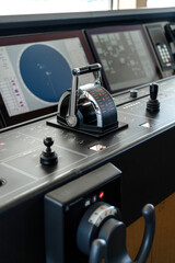 Detail shot of the throttle controls, radar and ship's systems in the bridge of a modern superyacht, with dark leather interior
