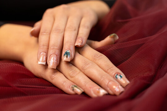 Christmas nail design, woman's hands with Christmas tree and candy cane design. Merry Christmas. Candy cane nails. Snowflake nails. Winter nails. Red fabric