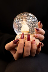 woman with red nails holding a snow globe, shiny red nails and heart emoji, christmas concept