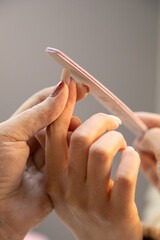 A professional nail technician creates nail designs on women's hands in a beauty salon. Equipment used in manual nail design