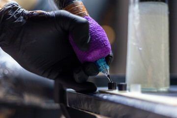 Close-up shot of a tattoo artist using a tattoo machine to create a detailed design on a client’s...