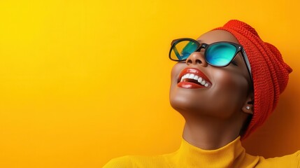 A joyful woman in sunglasses and a red headwrap beams a wide smile against a bright yellow backdrop, capturing a moment of happiness and vibrant fashion style.