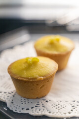 A beautifully arranged plate of lemon tarts, showcasing their vibrant yellow filling and delicate pastry crust, invites you to indulge in a delightful culinary experience. The smooth lemon curd