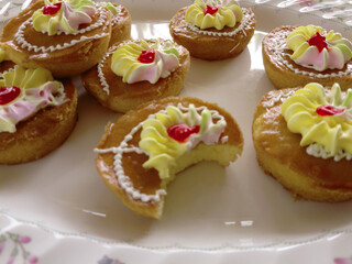 Mini cakes coated with caramel and piped with whipped cream.