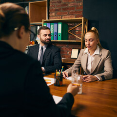 Two professionals in formal attire actively participate in business meeting, with office shelves in background. Professional collaboration. Concept of business, brainstorming, corporate lifestyle