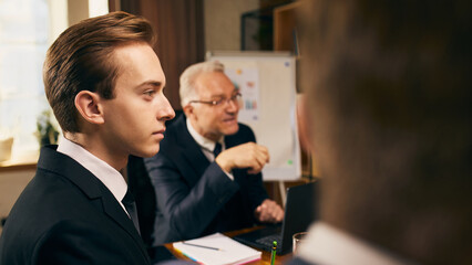 Elderly businessman and young team listening to colleagues expressing their ideas. corporate meeting. Strategic business session, brainstorming. Concept of business, teamwork, collaboration