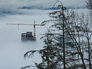 Building under construction in Burnaby, BC,  and construction crane enveloped in cloud cover.