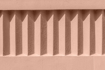 Mocha Mousse background Color of 2025 year. Beige exterior stucco wall with repeating details. Rough surface in the sun with shadows. Rough texture and background