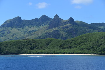 A lush green tropical paradise island with palm trees and white sandy beaches on Fiji in the...
