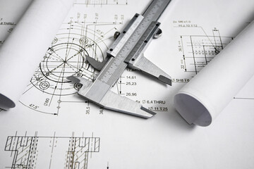 Caliper rests on rolled blueprints, highlighting the importance of precise measurements in...