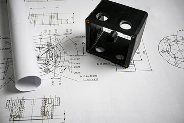 Black plastic prototype lying on technical drawing with measurements, showcasing precision and...