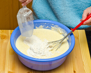 Making pancake batter. Pouring flour.