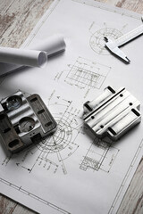Metal machined parts lying on a technical drawing with a caliper, showcasing precision engineering...