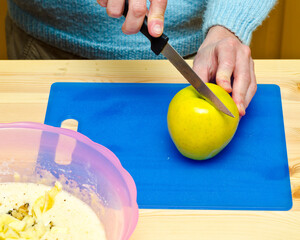 Making cookies. The cook has added walnut and starts to cut apple.