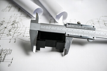 Caliper measuring a plastic component on top of technical drawing, engineering and quality control...