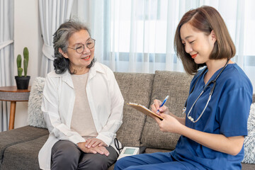 senior woman giving health interview to visiting nurse,having paper clipboard taking patient data...