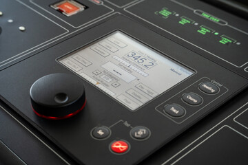 Detail shot of the throttle controls, radar and ship's systems in the bridge of a modern superyacht, with dark leader interior © lupiphoto