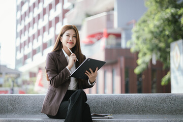 Confident businesswoman walks down a lively city street with laptop in hand. She exudes...