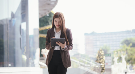 Confident businesswoman walks down a lively city street with laptop in hand. She exudes...