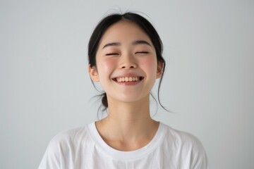 Asian woman laughing at joke  eyes closed  white background.