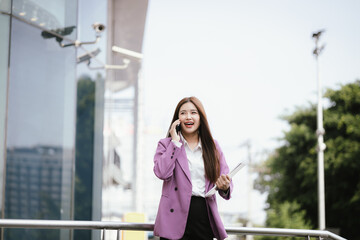 Fototapeta premium Beautiful Asian businesswoman in formal suit walking outdoors in city atmosphere