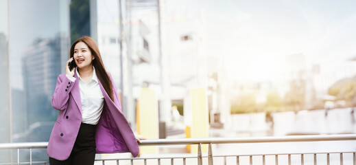 Fototapeta premium Beautiful Asian businesswoman in formal suit walking outdoors in city atmosphere
