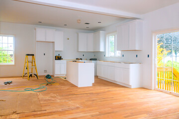 Bright, airy kitchen features new white cabinets hardwood flooring as renovations are underway during construction