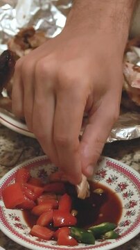 Eating lechon manok and dipping it in sawsawan soy sauce with bare hands that shows a candid and authentic Filipino cultural cuisine