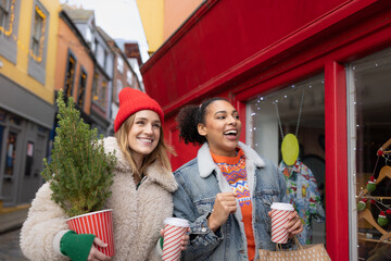 Friends happily Christmas shopping walking down a street