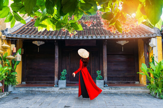 Young Vietnam woman wearing Ao Dai culture traditional walking on local street at Hoi an, Vietnam.