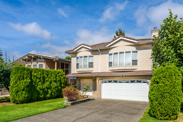 Two story stucco luxury house with nice summer  landscape in Vancouver, Canada, North America. Day time on June 2024.