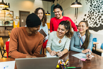 Coworkers collaborating on project using laptop in modern office