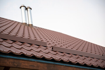 Brown metal snow guard on roof corrugated tile